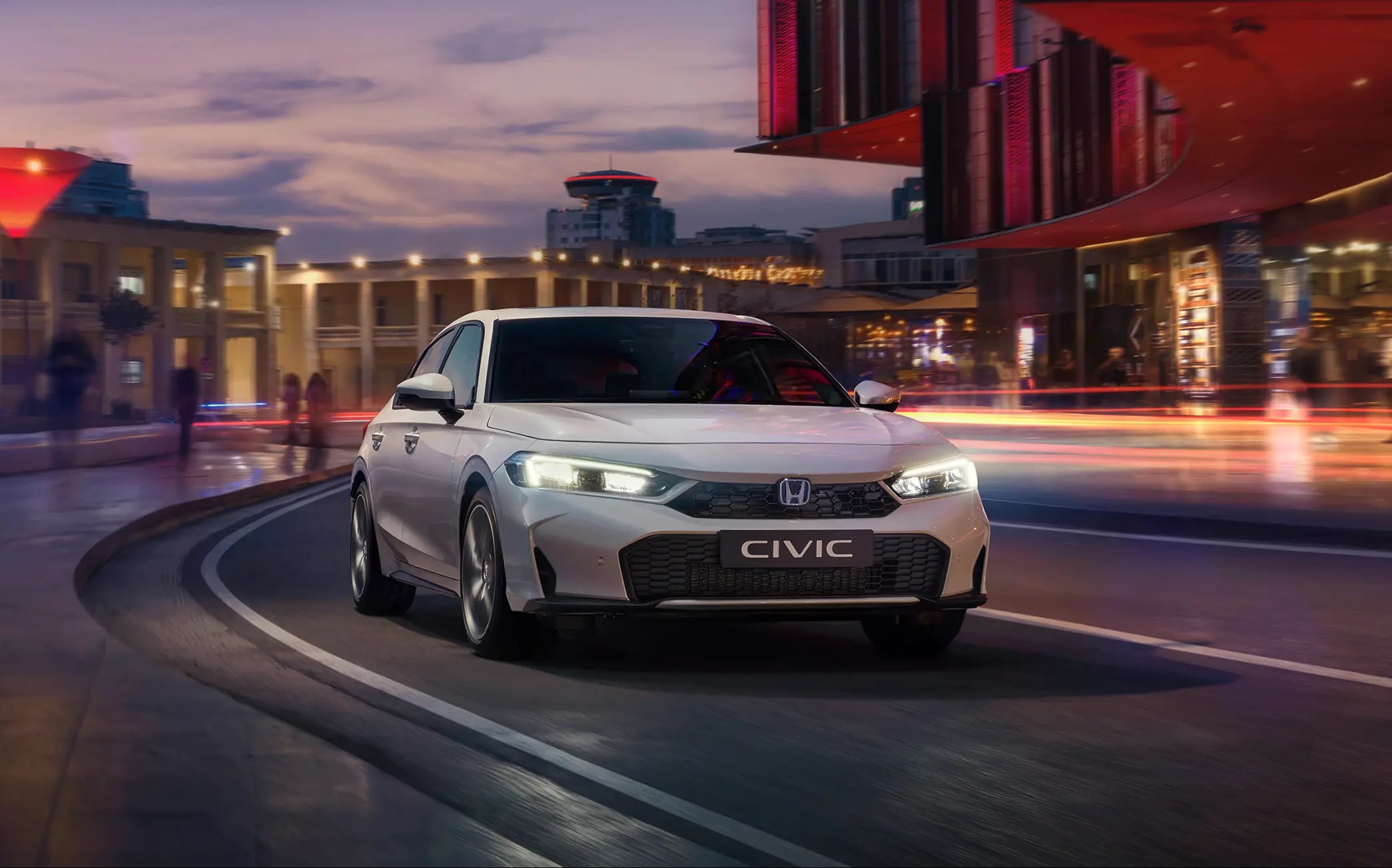Honda Civic Hybrid pri jazde mestom za úsvitu.